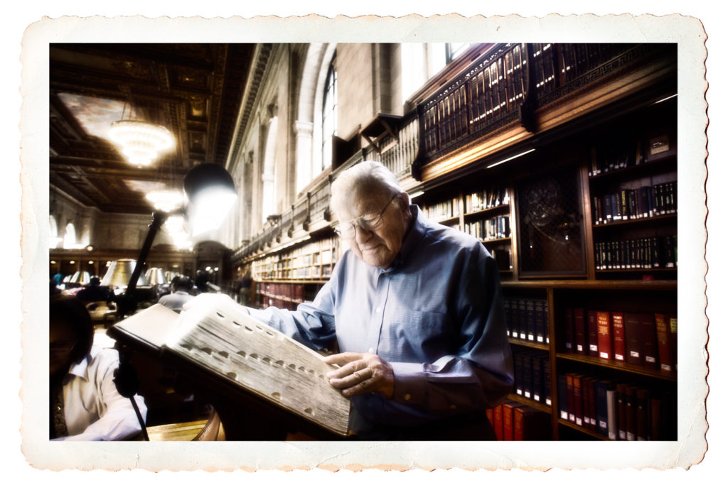 Postcard photo of an elderly man looking at large historical books in New York City Public Library